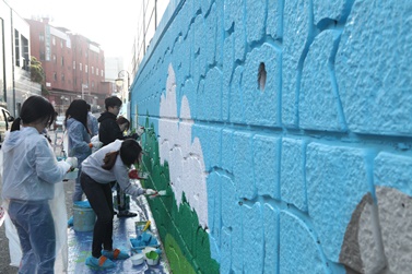 동아쏘시오그룹 벽화그리기 봉사활동에 참여한 직원들이 서울 동대문구 회기동 회기역 인근 담벽에 벽화를 그리고 있다.