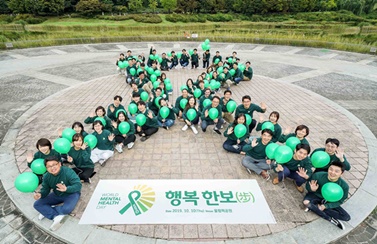 한국룬드벡 임직원들이 ‘세계 정신건강의 날’을 기념해 대형 초록 리본을 만드는 세리머니를 펼치고 있다.