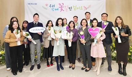 한국애브비 부서장들이 새로운 오피스에 봄이 왔음을 알리는 화사한 꽃들로 꾸며진 꽃길에서 첫 출근하는 직원들에게 꽃을 선물하고 있다.